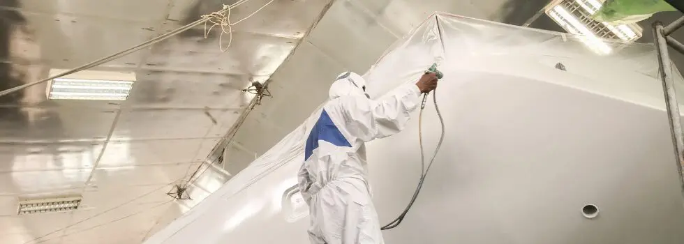 a man in a white suit painting a white boat